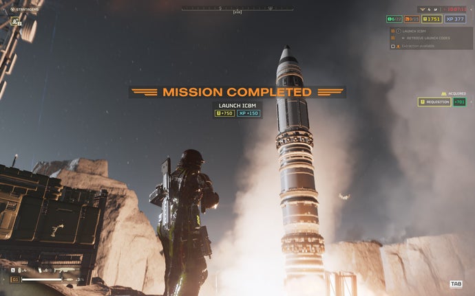 Helldivers 2 screenshot - The player-character looks up at a rocket as it launches. The game’s UI states: mission completed - launch ICBM.