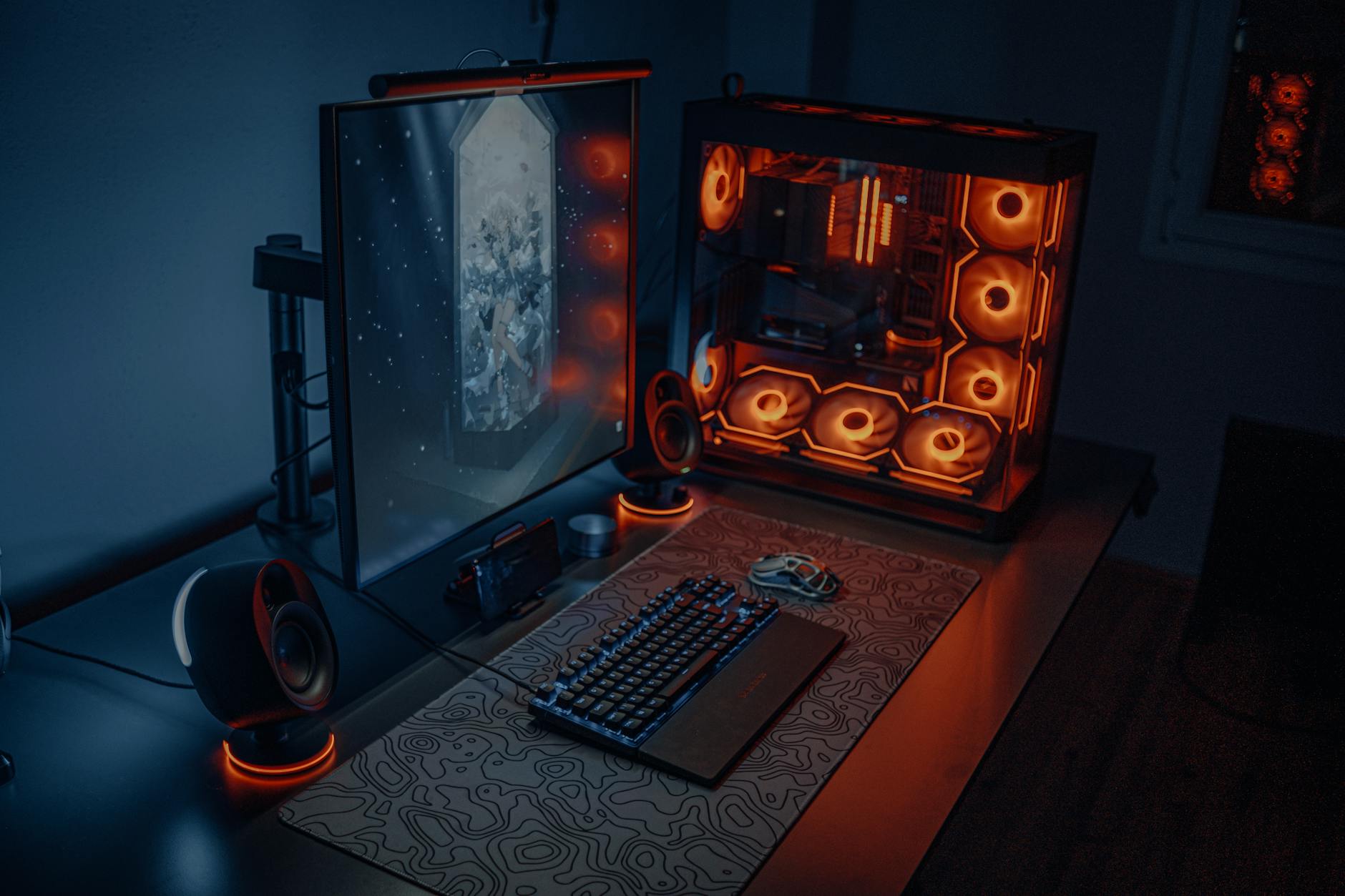 High-end gaming PC setup with RGB lighting and multiple monitors displaying performance metrics