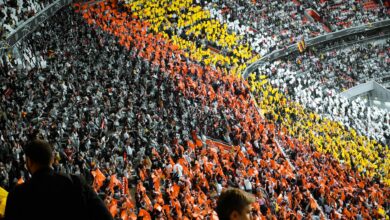 Packed college football stadium with enthusiastic crowd cheering during game