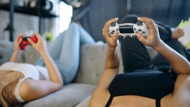 Group of friends playing video games together on couch with controllers