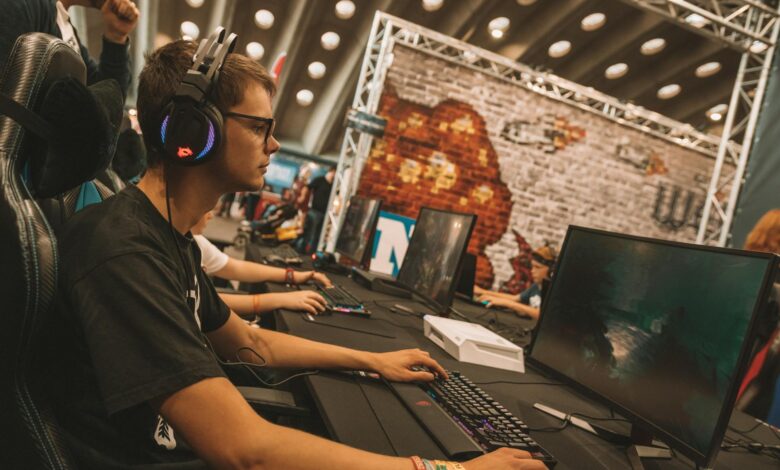 Professional esports tournament setup with multiple gaming stations and large screens displaying competition