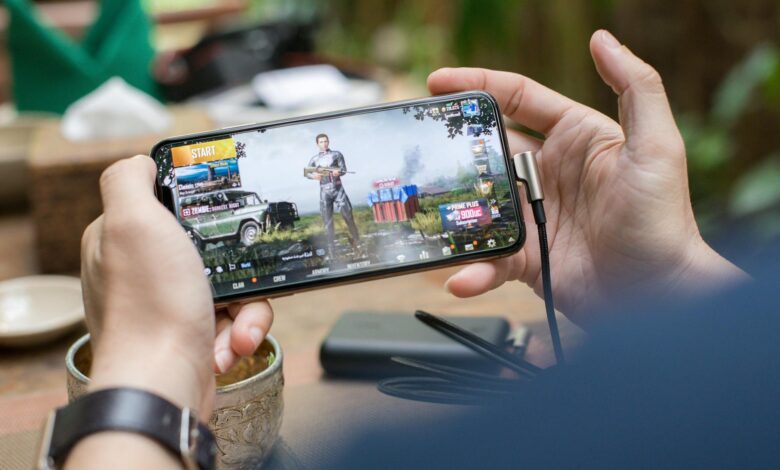 Person playing mobile games on smartphone with gaming interface visible on screen
