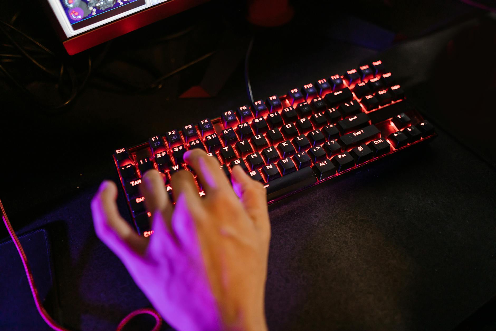 Close-up of illuminated mechanical gaming keyboard with RGB backlighting on dark gaming desk
