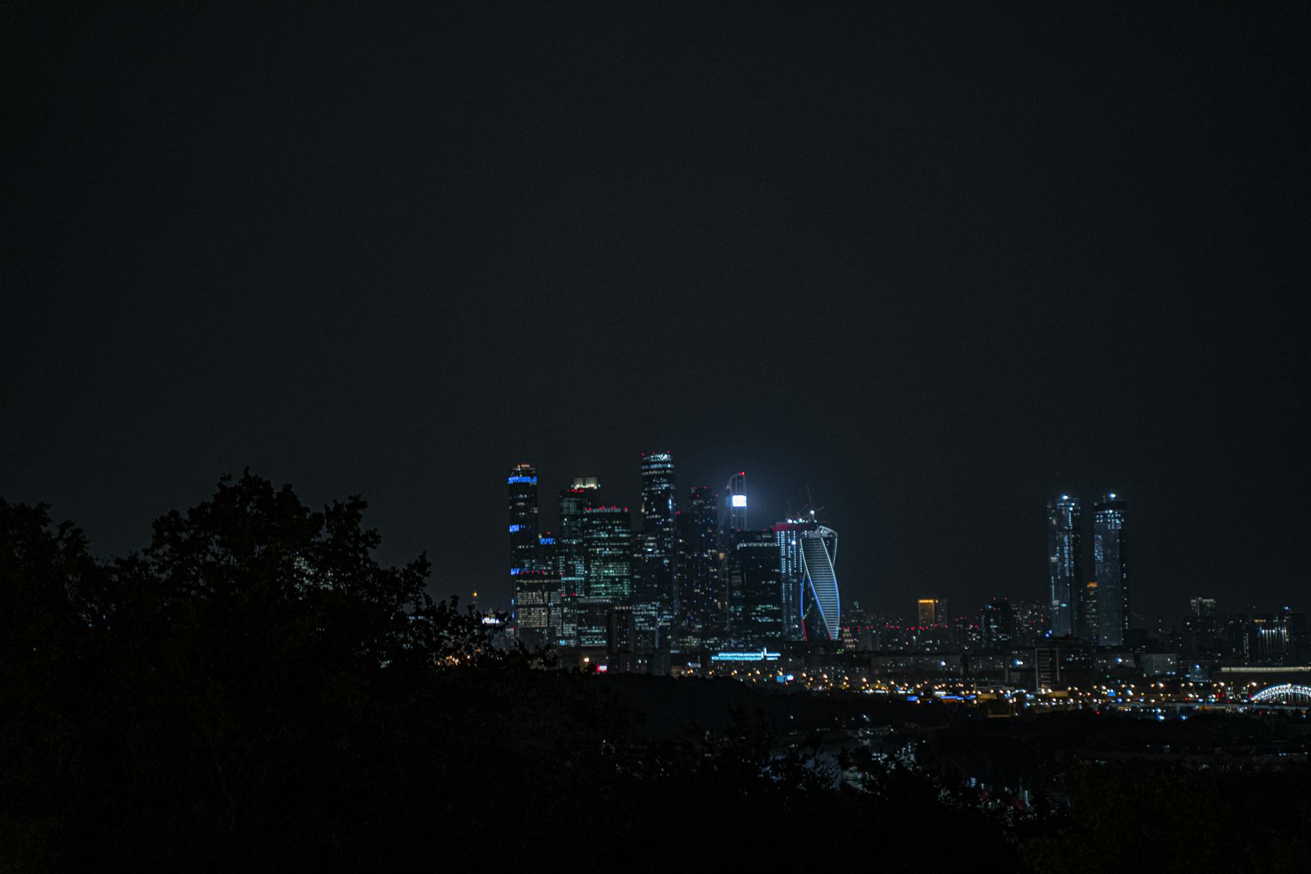 Urban city skyline at night with illuminated skyscrapers and reflective surfaces