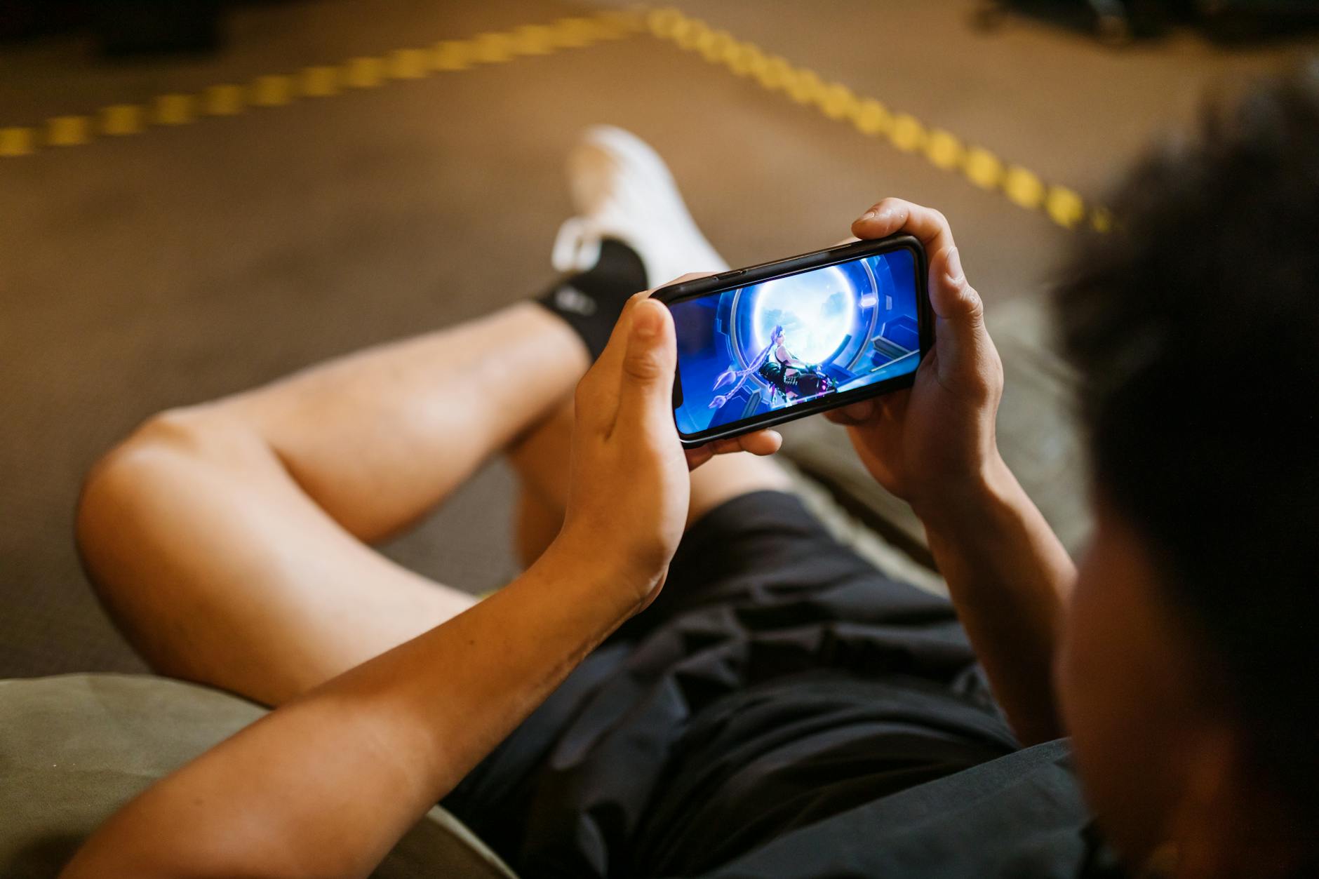 Person playing competitive mobile game on smartphone with focused concentration