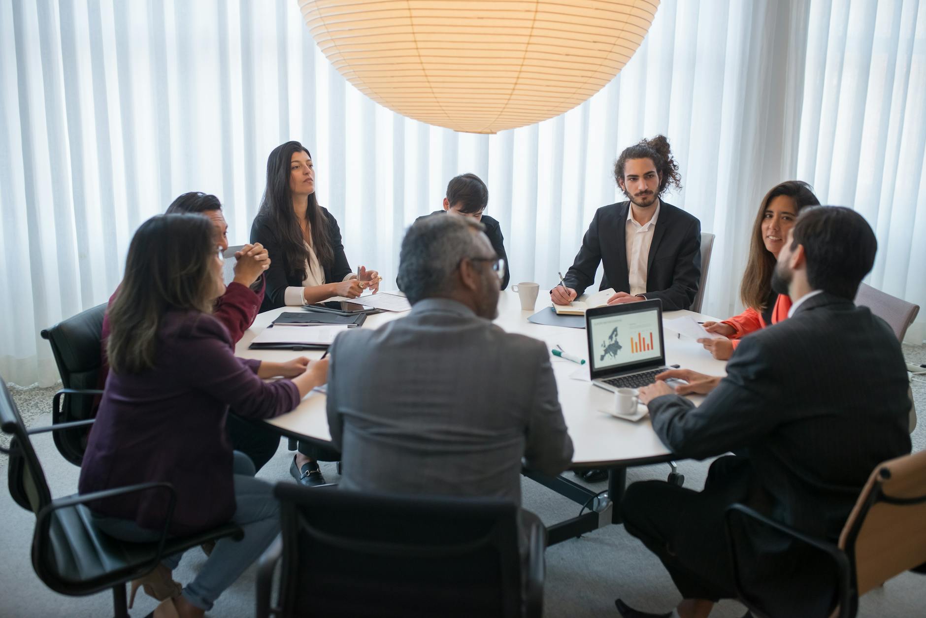 Group of people collaborating around computer screens in modern office environment