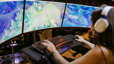 Three gaming monitors displaying cooperative multiplayer gameplay in a dark room