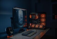 A modern mid-tower PC case with wood front panel sitting on a clean desk setup