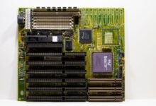 High-end AMD X870E gaming motherboard with VRM heatsinks and RGB lighting visible on a dark surface