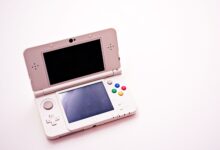 A handheld PC gaming device held in two hands against a neutral background