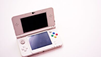 A handheld PC gaming device held in two hands against a neutral background