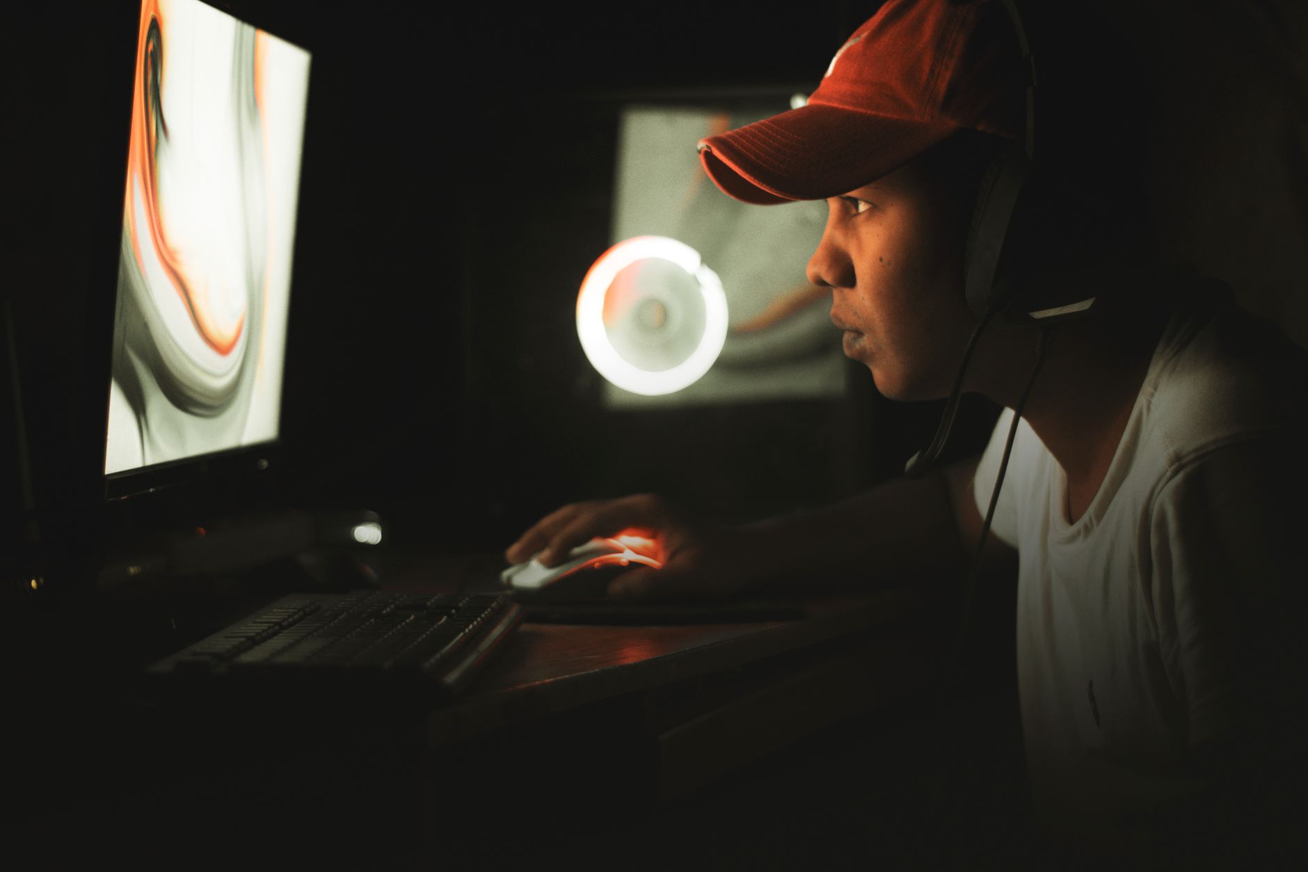 Person playing a game on a large 4K monitor in a dimly lit gaming room